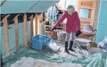 Elke Ibrahim, vice-chair of the Glace Bay Her­itage Mu­seum So­ci­ety, stands among buck­ets and plas­tic stor­age bins on the third floor of the her­itage build­ing. Un­der the bins, which are be­ing used to catch wa­ter leak­ing through the roof, are lay­ers of plas­tic to deal with the over­flow of wa­ter. Ibrahim said roof re­pairs are es­ti­mated to cost more than $230,000 and are needed this year or the mu­seum will have to close.