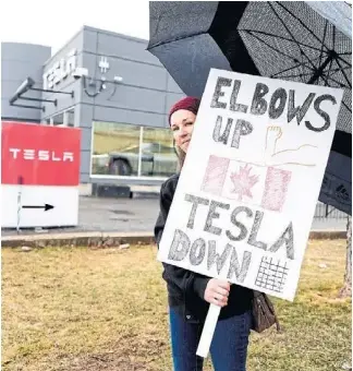 A pro­tester attends a rally out­side an Ott­awa Telsa deal­er­ship last week­end. In Janu­ary, four Tesla deal­er­ships claimed $43.1 mil­lion in rebates under a now­defunct fed­eral pro­gram for 8,653 elec­tric vehicle sales in a 72­hour period.