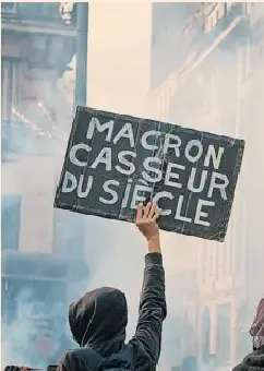 Below: a pro­tester waves a sign in Paris last Sat­urday read­ing ‘Mac­ron the wrecker of the cen­tury’