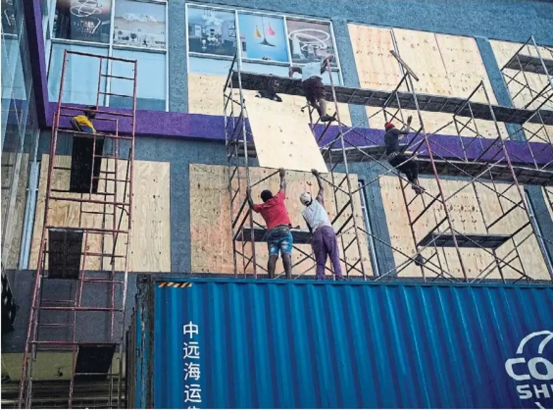 Workers board up shop windows on Sunday ahead of Hurricane Melissa's arrival in Kingston, Jamaica. The Category 5 storm was expected to make landfall on Tuesday and officials warn it could be one of the worst in Jamaica's history.