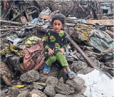 A girl sits on the rubble of her dam­aged home Sunday fol­low­ing Fri­day's flash flood­ing in Buner, in north­w­est Pakistan.