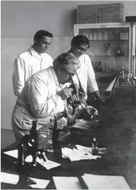 J. PIN­TO/ACER­VO CA­SA DE OSWAL­DO CRUZ ao mi­cros­có­pio, acom­pa­nha­do do fi­lho Ben­to Cruz (à di­rei­ta) e pe­lo ci­en­tis­ta Car­los Bur­le de Figueiredo (atrás) Oswal­do Cruz