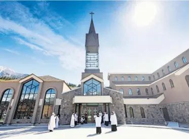 Bishop Wil­liam McGrat­tan and lo­cal priests take part in of­fi­cially un­lock­ing the doors dur­ing the ded­i­ca­tion cer­e­mony of the new Shrine Church of Our Lady of the Rock­ies in Can­more, Alta., on Satur­day.