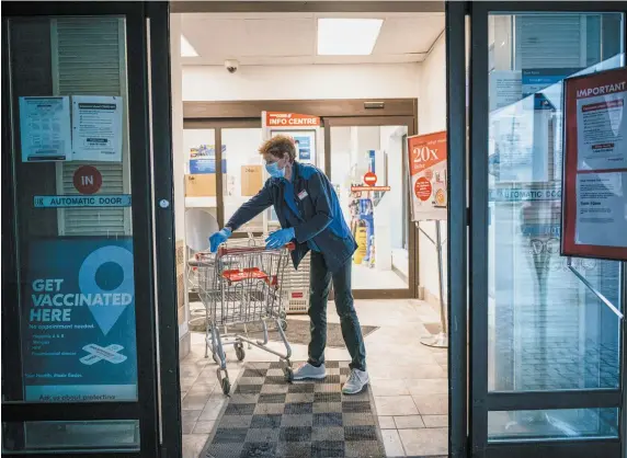 Sue Marit dis­in­fects shop­ping carts in a Shop­per’s Drug Mart in Bobcaygeon, Ont., on March 29. North Amer­ica has lost nearly 20 mil­lion jobs in about three weeks, and the pan­demic is cost­ing the econ­omy tril­lions by forc­ing peo­ple to stay at home.