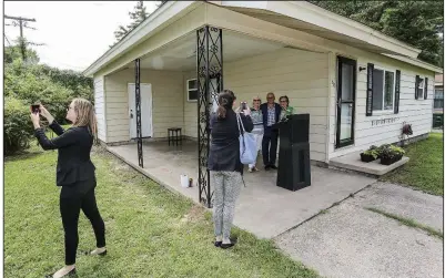 Mandy Davis (left), direc­tor of the Jeri­cho Way Re­source Cen­ter, takes a photo of peo­ple at Tues­day’s cer­e­mony mark­ing com­ple­tion of ren­o­va­tions on a Heather Lane house in Lit­tle Rock. Mean­while, Lit­tle Rock City Direc­tor Capi Peck pho­to­graphs speak­ers at the cer­e­mony: (from left) Kay Ger­hardt and Chuck Levesque, both with Depaul USA; and Lit­tle Rock City Direc­tor Kathy Webb.