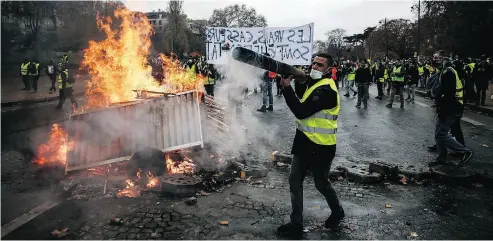 Pro­test­ers build a bar­ri­cade in Paris dur­ing a protest of yel­low vests against ris­ing oil prices and liv­ing costs. The protests are be­ing closely watched in Canada by those who see a par­al­lel be­tween fuel taxes and car­bon taxes.