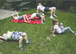 Coun­sel­lor Zev Wood, seen in back­ground, leads five-year-olds in yoga ex­er­cises dur­ing a back­yard sum­mer camp pro­gram in Mon­treal West or­ga­nized by pan­demic-in­spired com­pany Learn ’N Play on Wed­nes­day. Tak­ing part are Ben­jamin Macma­hon, front left, Me­gan Copeland, right, and, on red mat, twins Tobin and Rory Coughlin.