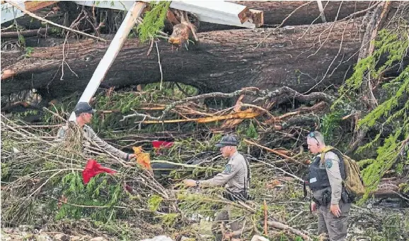 Texas Game Warden offi­cials comb through debris along the banks of the Guada­lupe River on Sat­urday.