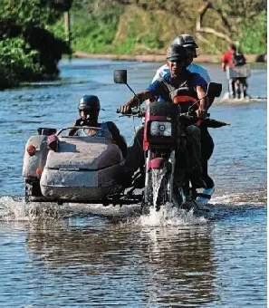 People tra­verse a road flooded by Hur­ricane Melissa on the south­ern coast of San­ti­ago de Cuba on Thursday.
