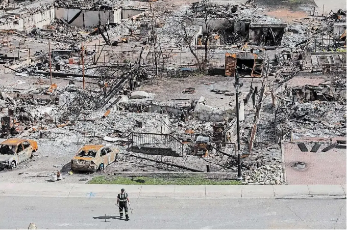 A worker walks through Jasper, Alta., last August, just weeks after a devastating wildfire swept through the town. One local official said the full residential rebuild will likely take five to 10 years.