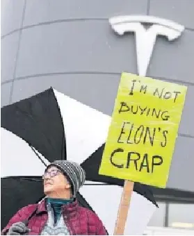 A pro­tester stands out­side a Tesla deal­er­ship in Ott­awa last week­end. The elec­tric vehicle maker has been the biggest recip­i­ent of Cana­dian EV rebates, claim­ing $713 mil­lion since 2019.